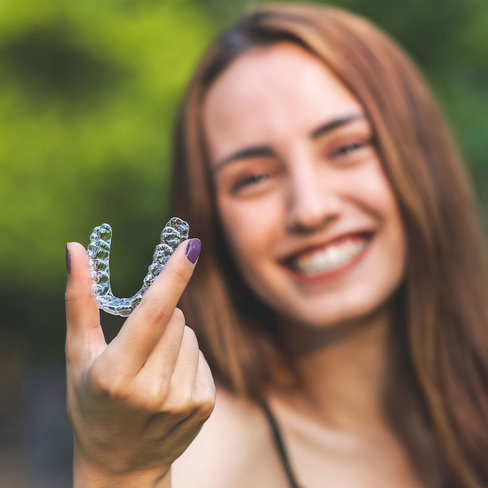A person is holding up a small, clear plastic tray with a single toothbrush-shaped object inside it.