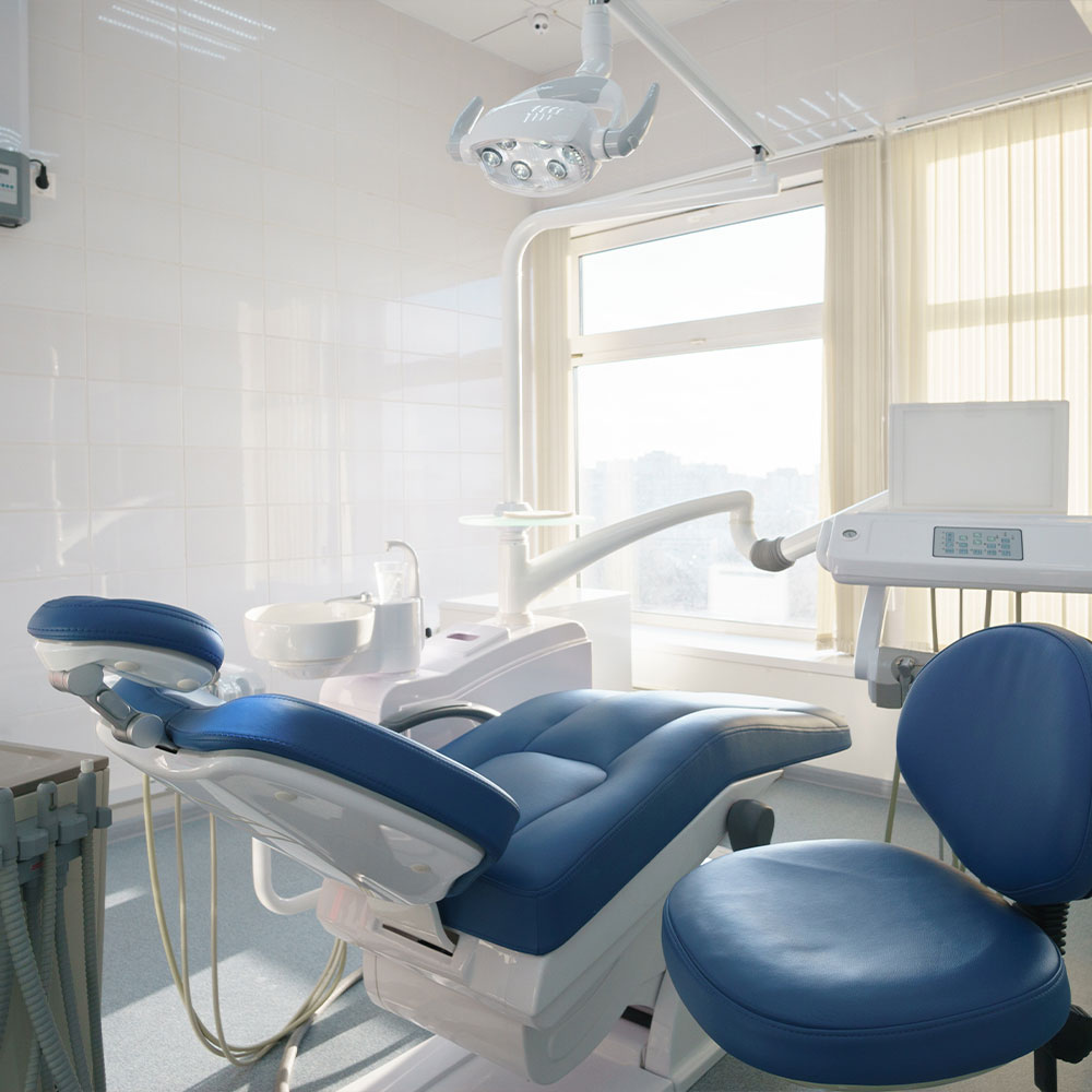 The image shows a dental office interior with a dental chair, a dental light, and various dental equipment.